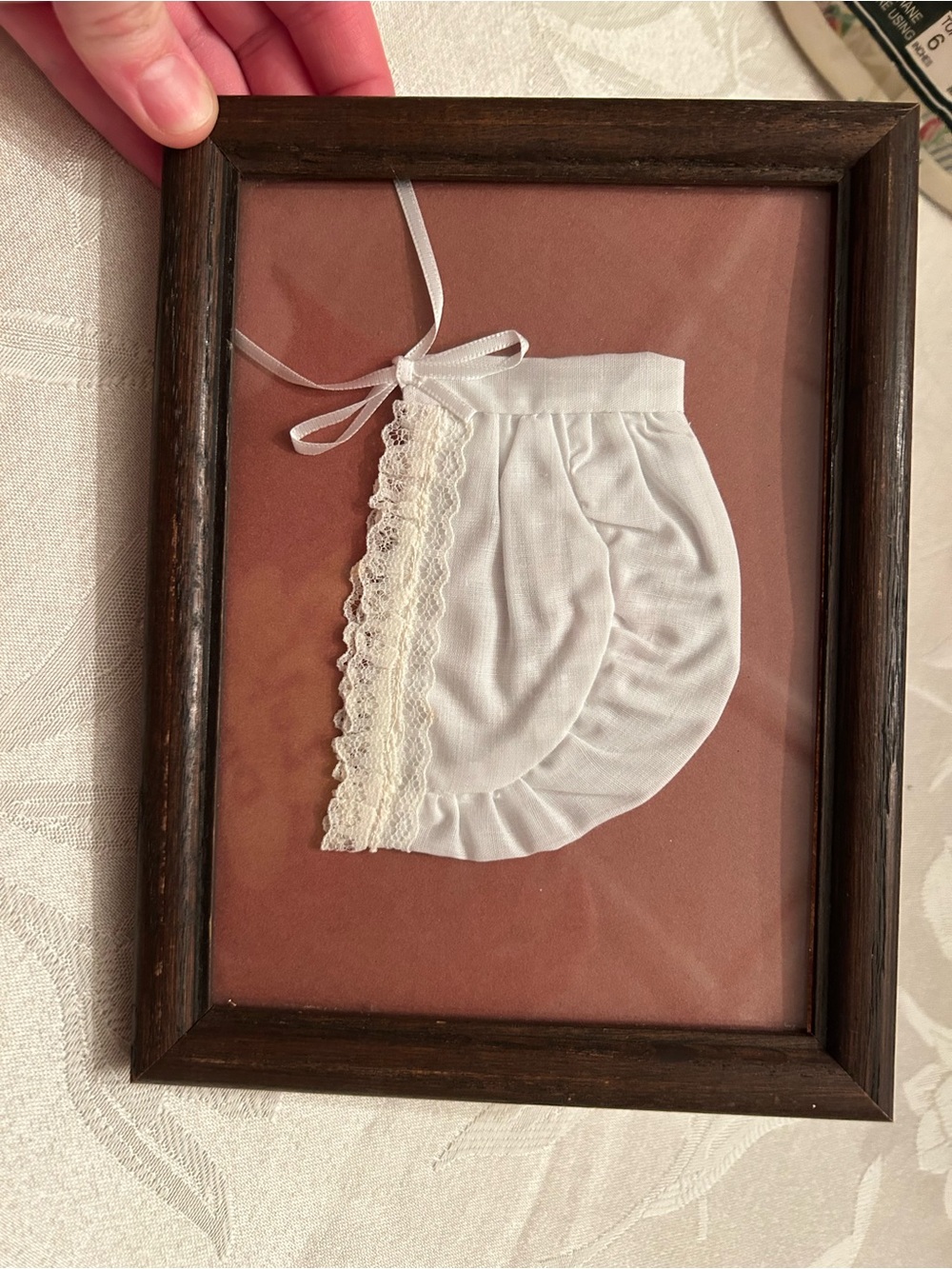 Vintage framed white fabric bonnet in dark wood frame